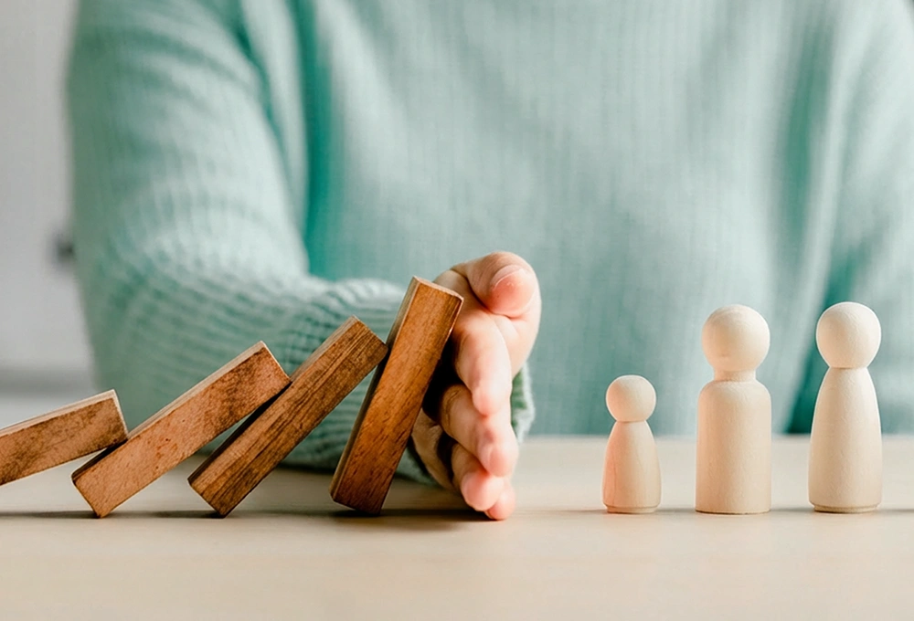 Une main stoppe des dominos en pleine chute